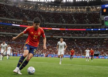 Spanish soccer player in red national team jersey dribbling at a World Cup match in Atlanta