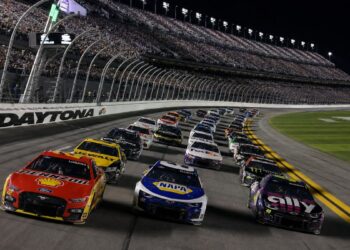 NASCAR Cup Series cars racing three-wide under the lights during a night race