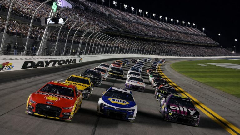 NASCAR Cup Series cars racing three-wide under the lights during a night race