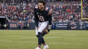 Caleb Williams scrambling and grabbing his right hamstring for the Chicago Bears
