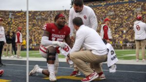 Oklahoma Sooners linebacker being attended to on the sideline after a knee injury during a game at Michigan Stadium