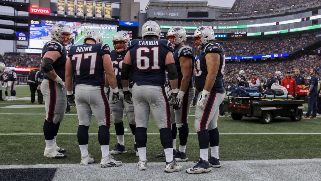 Patriots offensive line and medical staff on the sideline at Gillette Stadium after Mike Onwenu ankle injury