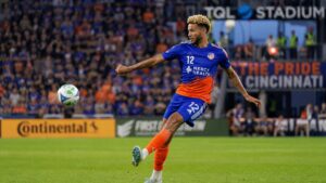 Miles Robinson clearing the ball for FC Cincinnati in his orange and blue kit