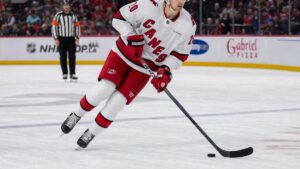Sebastian Aho of the Carolina Hurricanes skating with the puck in a white road jersey