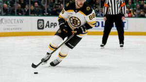 David Pastrnak skating with the puck for the Boston Bruins in a game at Dallas