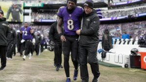 Lamar Jackson in Baltimore Ravens uniform dealing with an ankle injury on the sideline