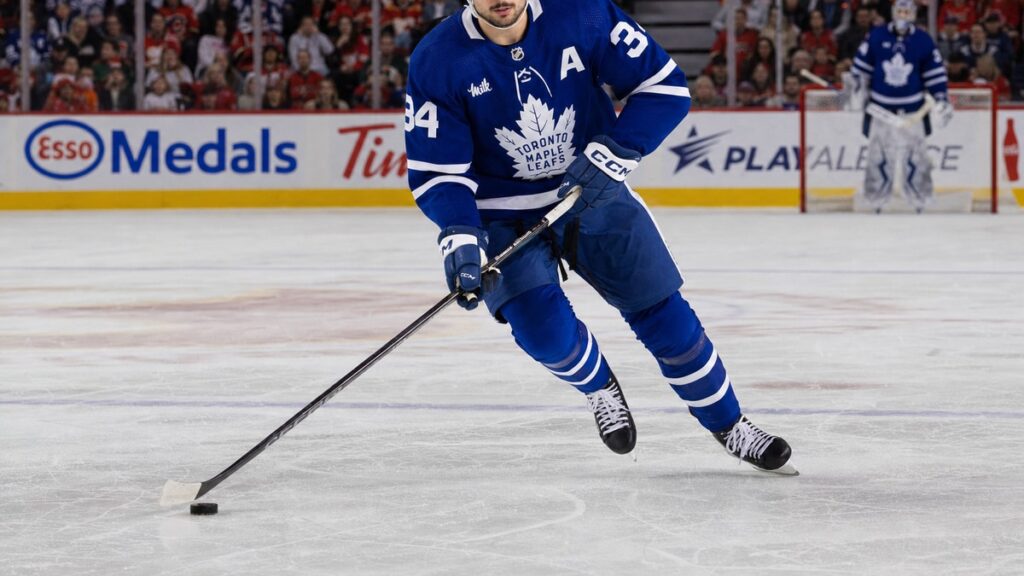 Auston Matthews of the Toronto Maple Leafs skating with the puck in a game at Calgary