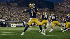 Notre Dame quarterback CJ Carr dropping back to pass under the lights in a college football night game
