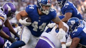 Giants running back Cam Skattebo carrying the football in a New York Giants home uniform